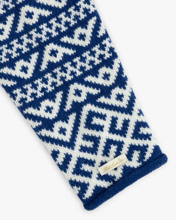 A Poros Jacquard Pullover sleeve with a white and blue geometric knit pattern and a small brand label at the cuff.
