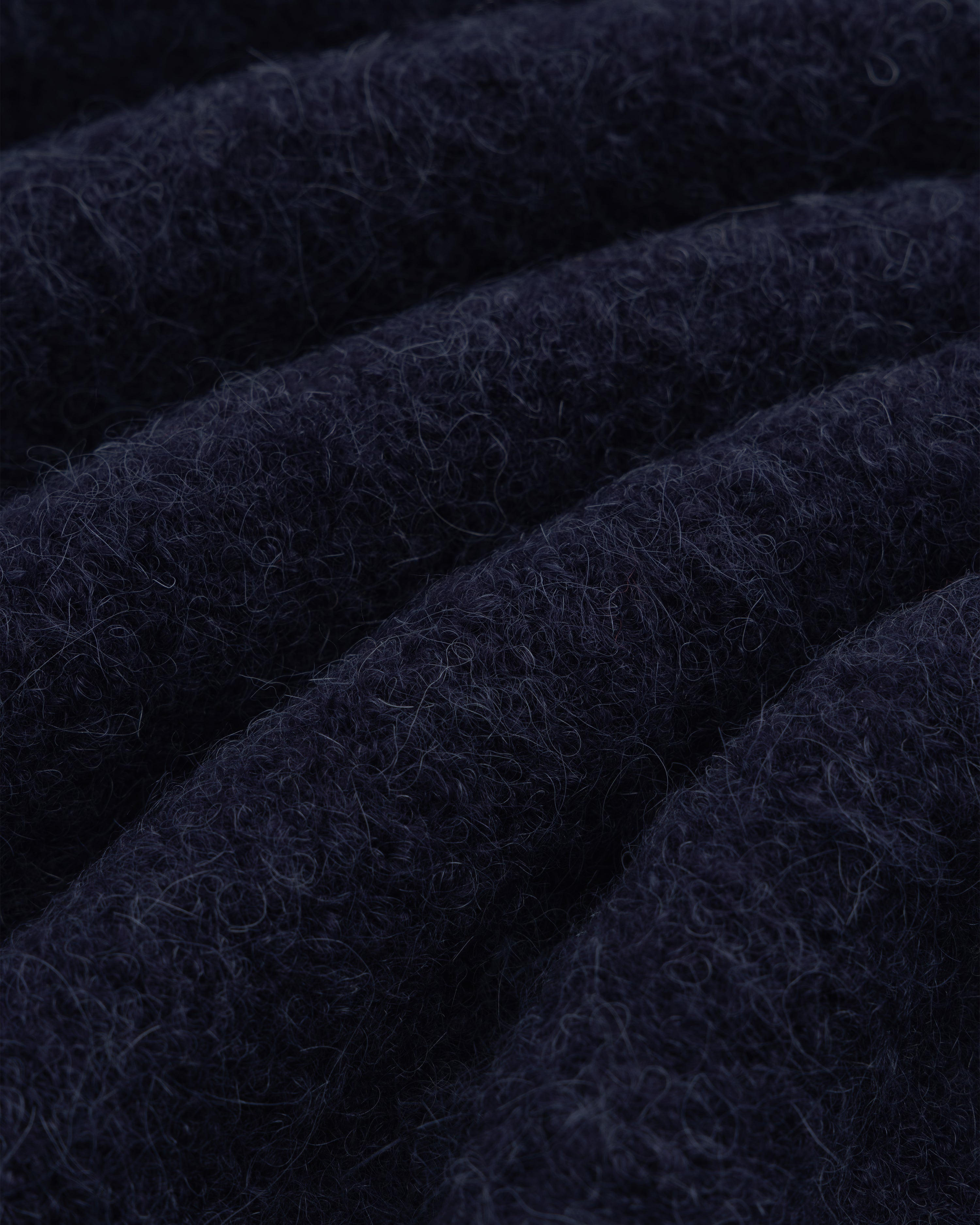 Close-up of dark navy blue alpaca wool from our Quarter Zip Sweater, showing soft texture and wavy ridges.