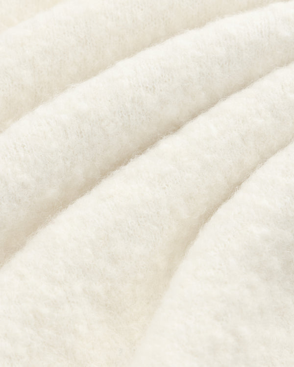 Close-up of the Alpaca Wool Quarter Zip Sweater’s soft, white texture with gentle, diagonal wavy folds.
