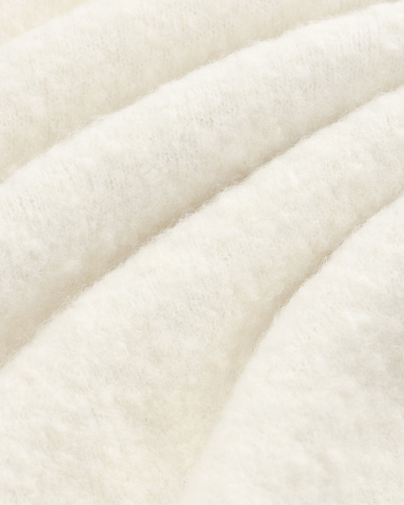 Close-up of the Alpaca Wool Quarter Zip Sweater’s soft, white texture with gentle, diagonal wavy folds.