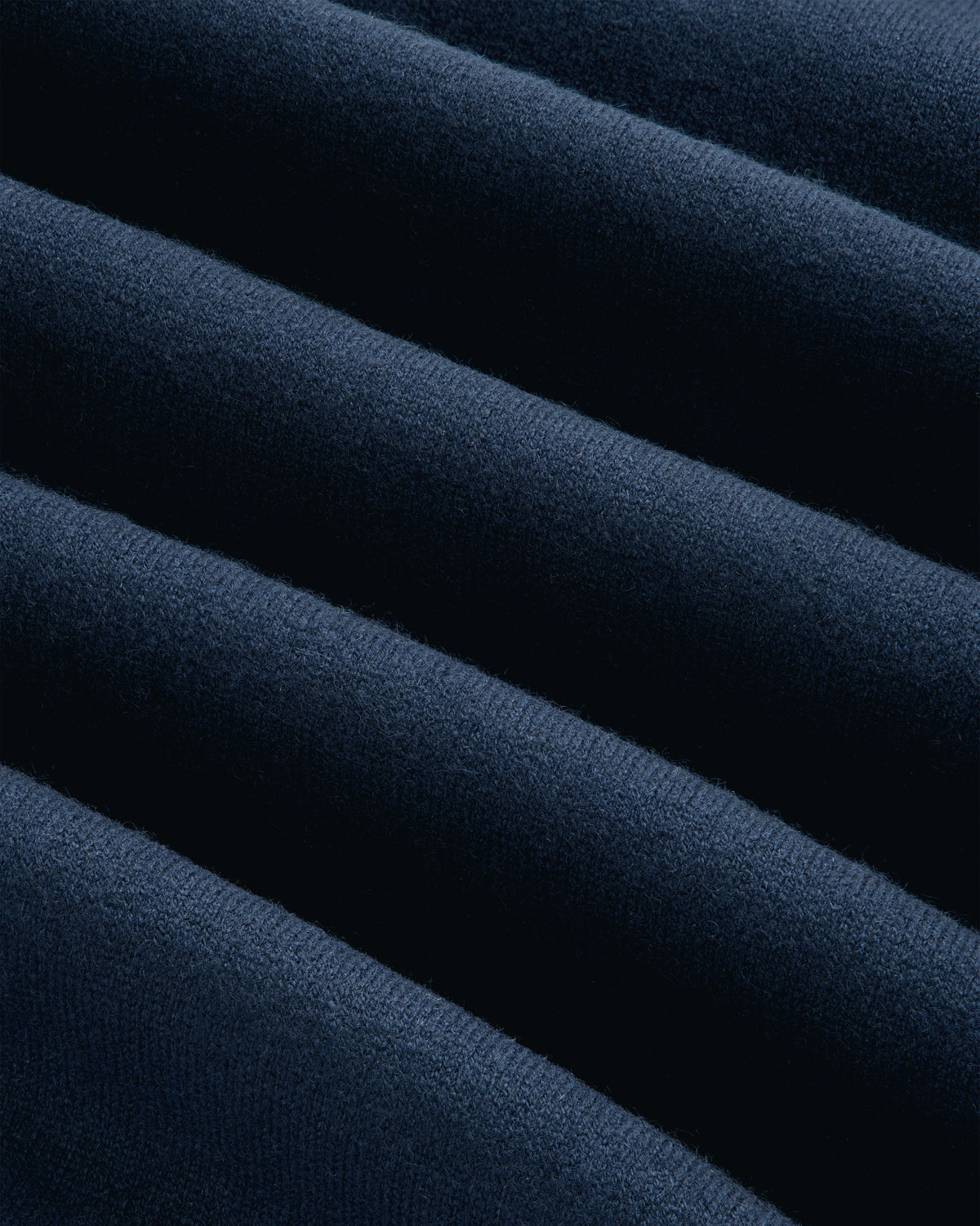 Close-up of soft Pavilion Cashmere Crewneck Sweatshirt in dark blue, with smooth, diagonal, wavy folds.