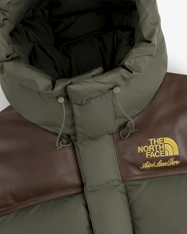 Close-up of a green and brown ALD / The North Face Baltoro Jacket with gold Aimé Leon Dore logo on the chest.