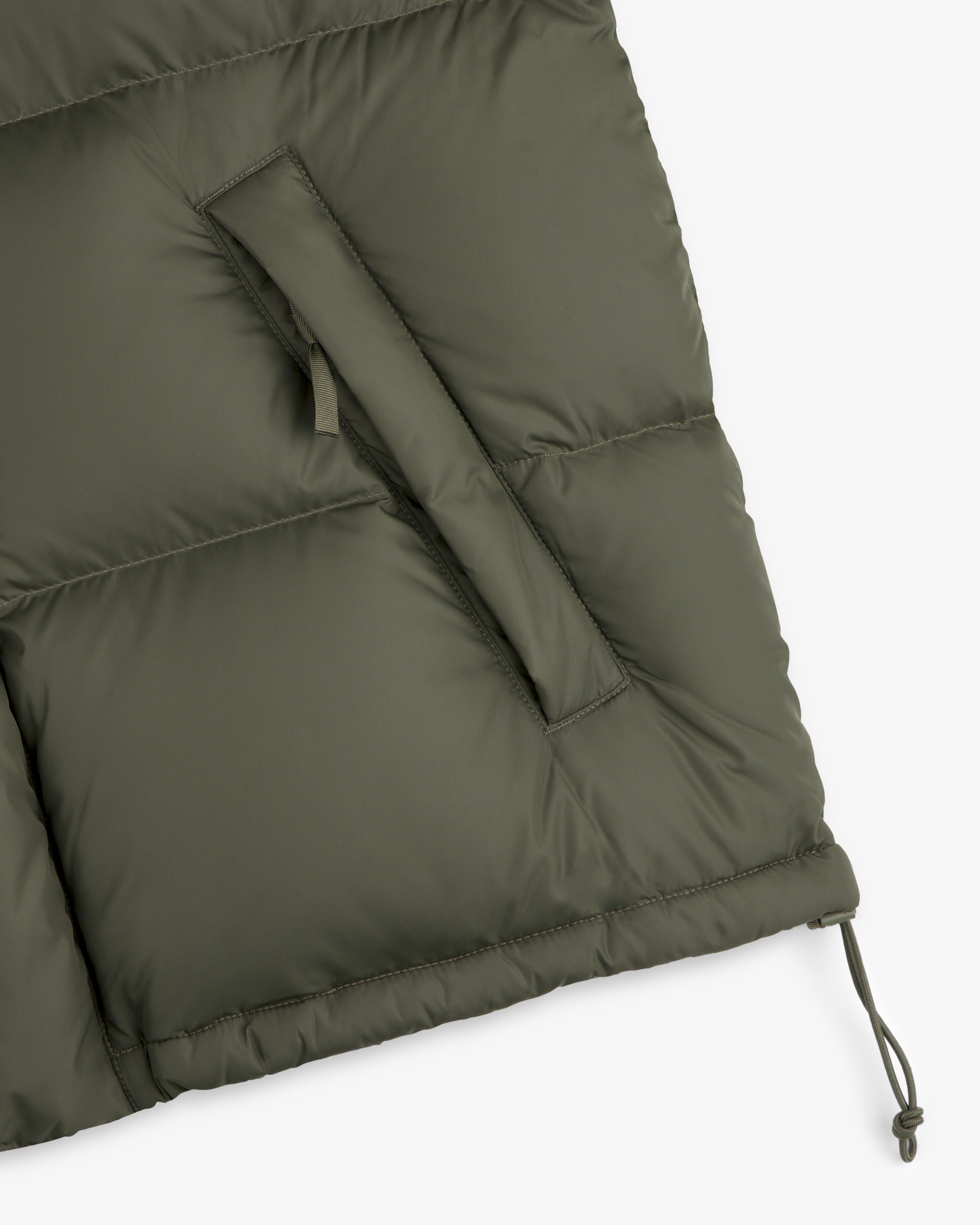 Close-up of the olive ALD / The North Face Baltoro Jacket with slanted pocket and adjustable drawstring hem.