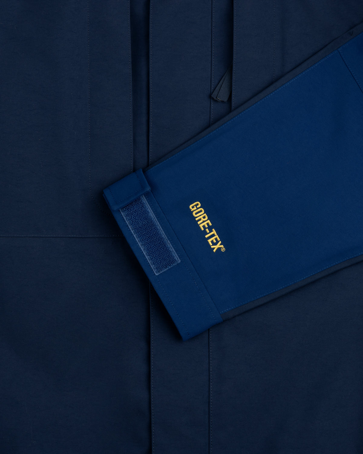A blue ALD/The North Face GORE-TEX 2000 Mountain Jacket sleeve with velcro rests on a matching blue background.