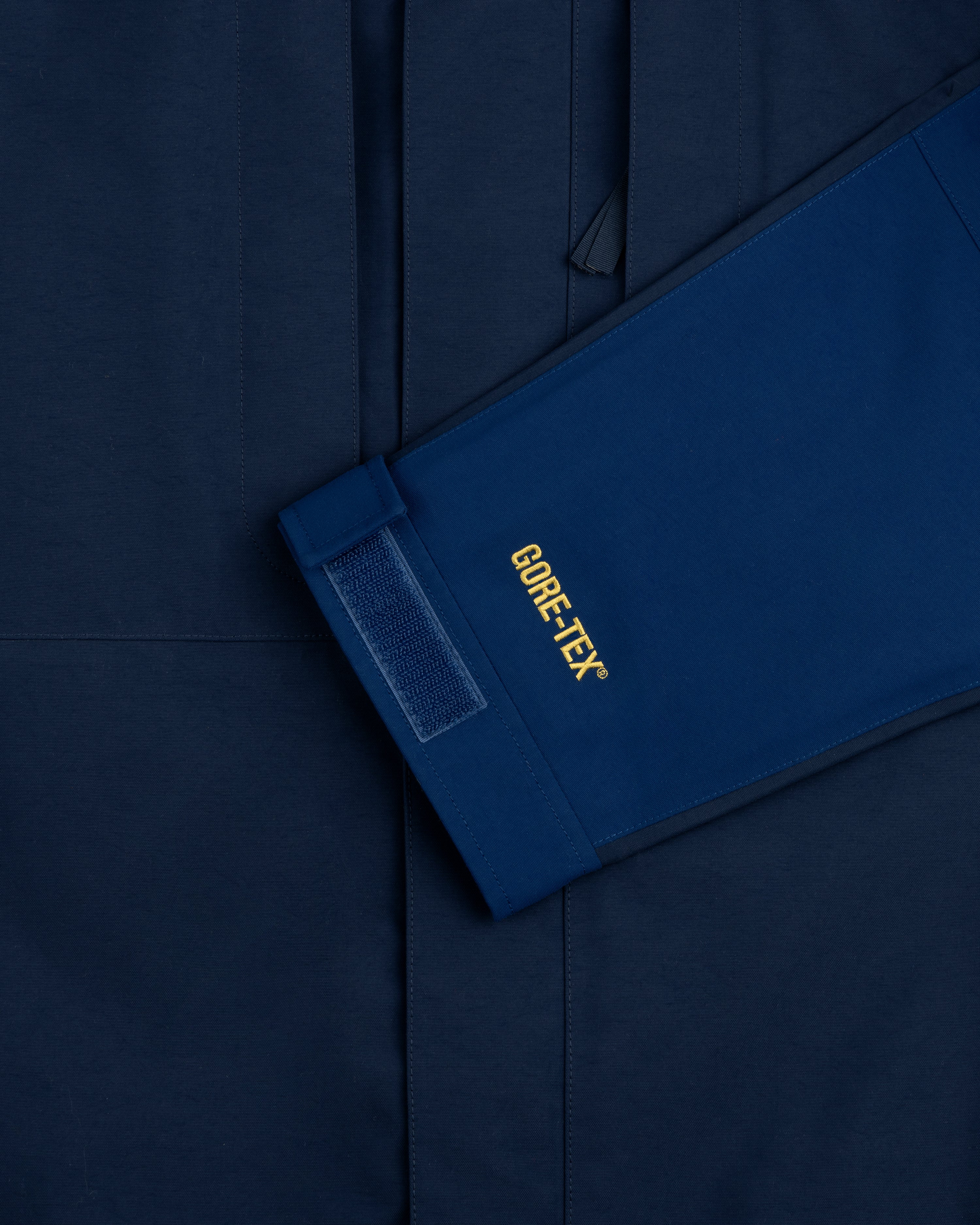 A blue ALD/The North Face GORE-TEX 2000 Mountain Jacket sleeve with velcro rests on a matching blue background.