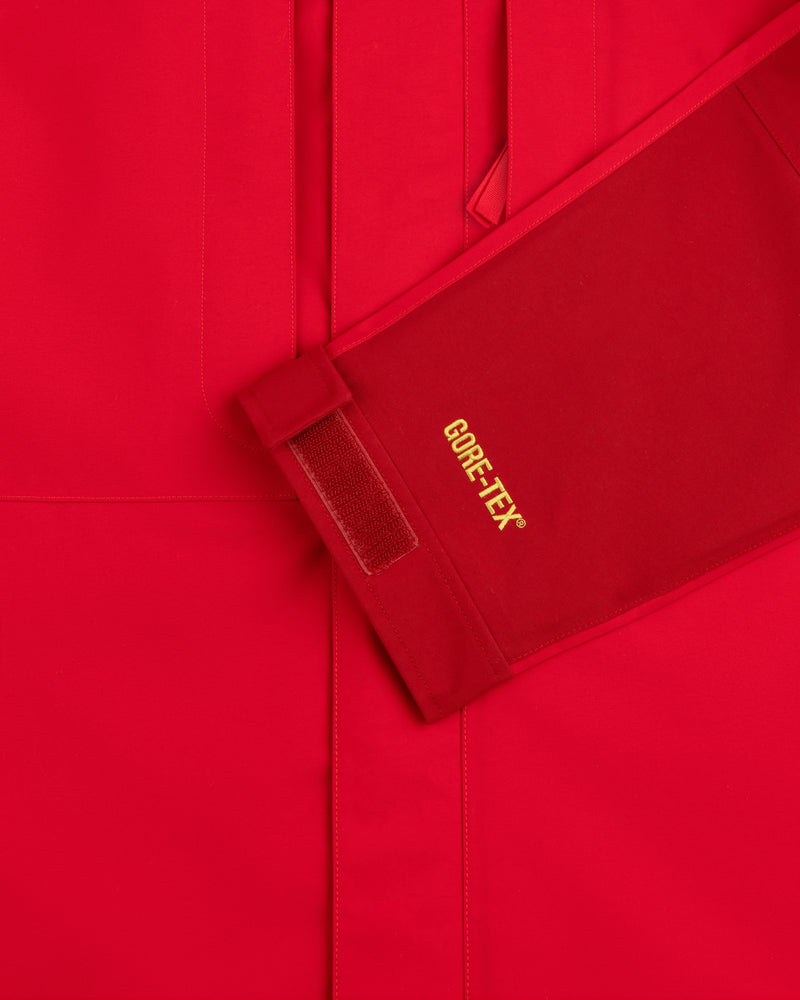 Close-up of ALD / The North Face GORE-TEX 2000 Mountain Jacket sleeve with yellow logo, Velcro strap, red background.