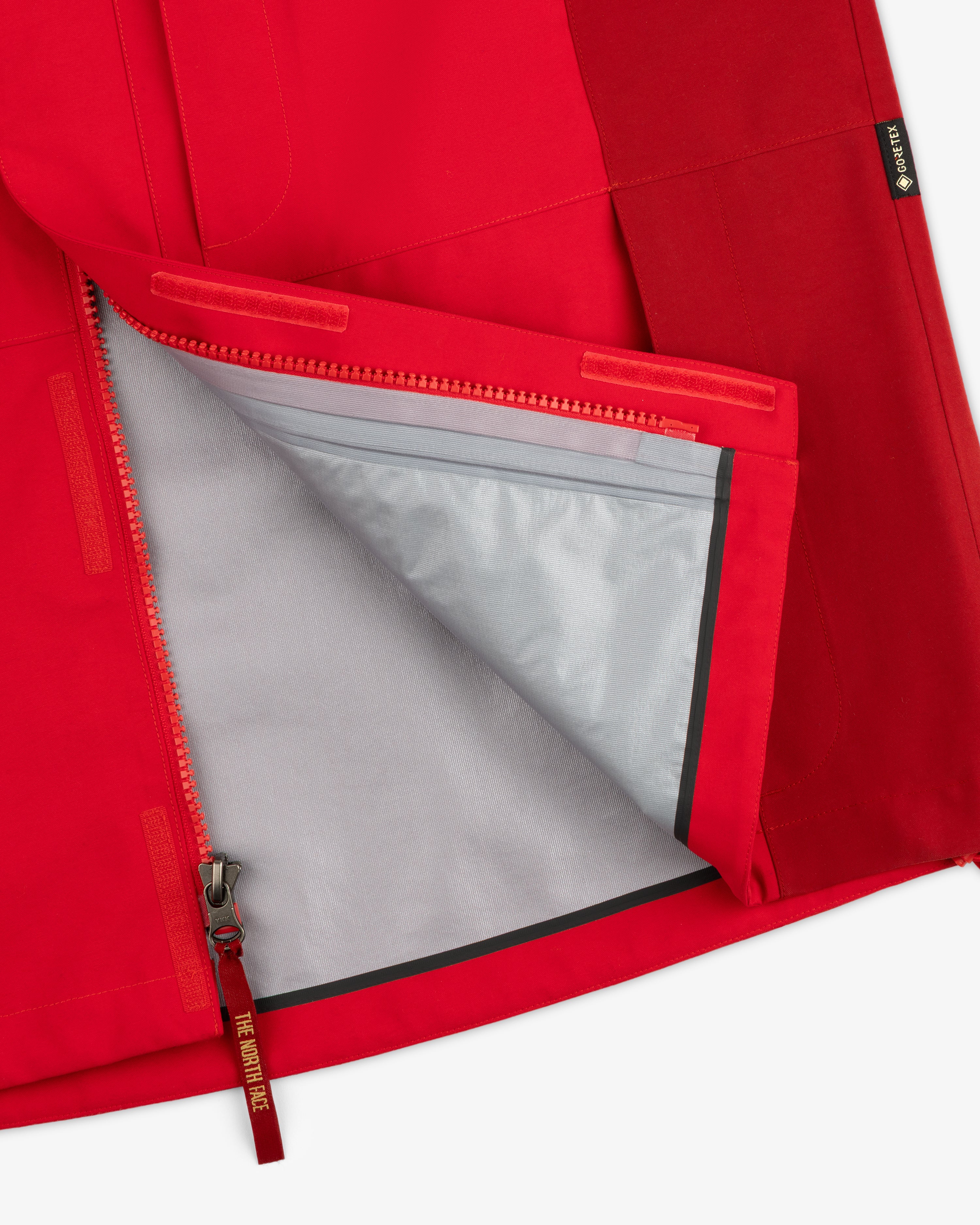 Close-up of the ALD / The North Face GORE-TEX 2000 Mountain Jacket, red, unzipped to show its gray lining.