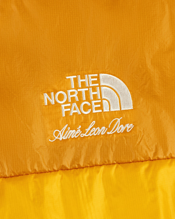 Close-up of yellow ALD / The North Face Reversible Pertex® Nuptse Jacket, white embroidery visible.