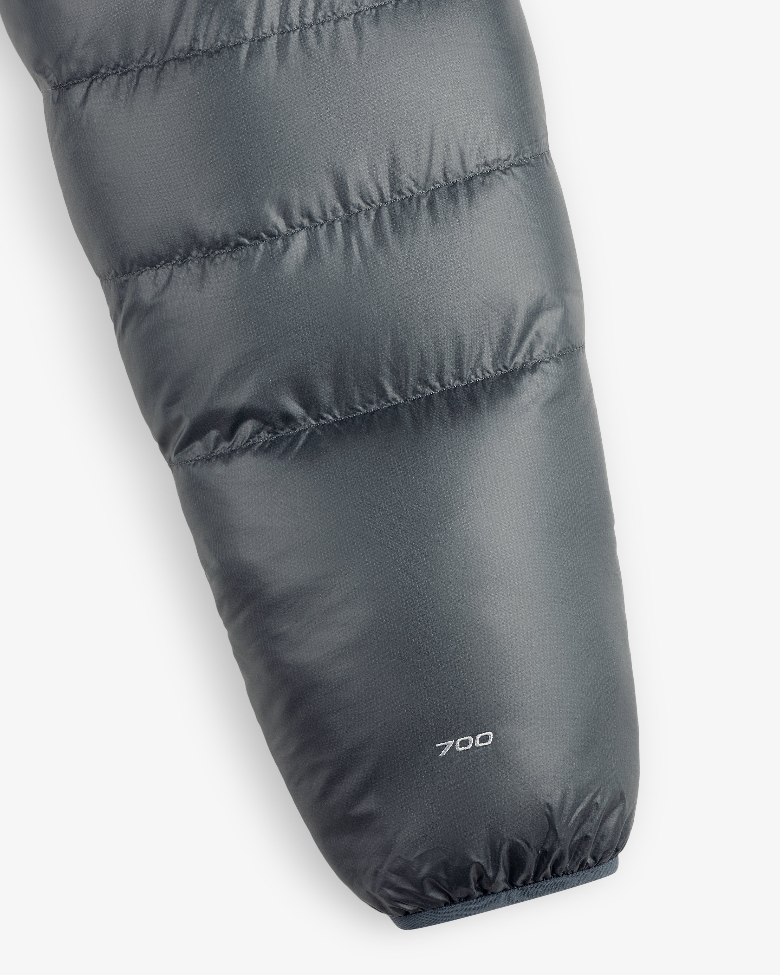 Close-up of an ALD/The North Face Reversible Pertex® Nuptse Jacket sleeve with “700” near the cuff on gray fabric.