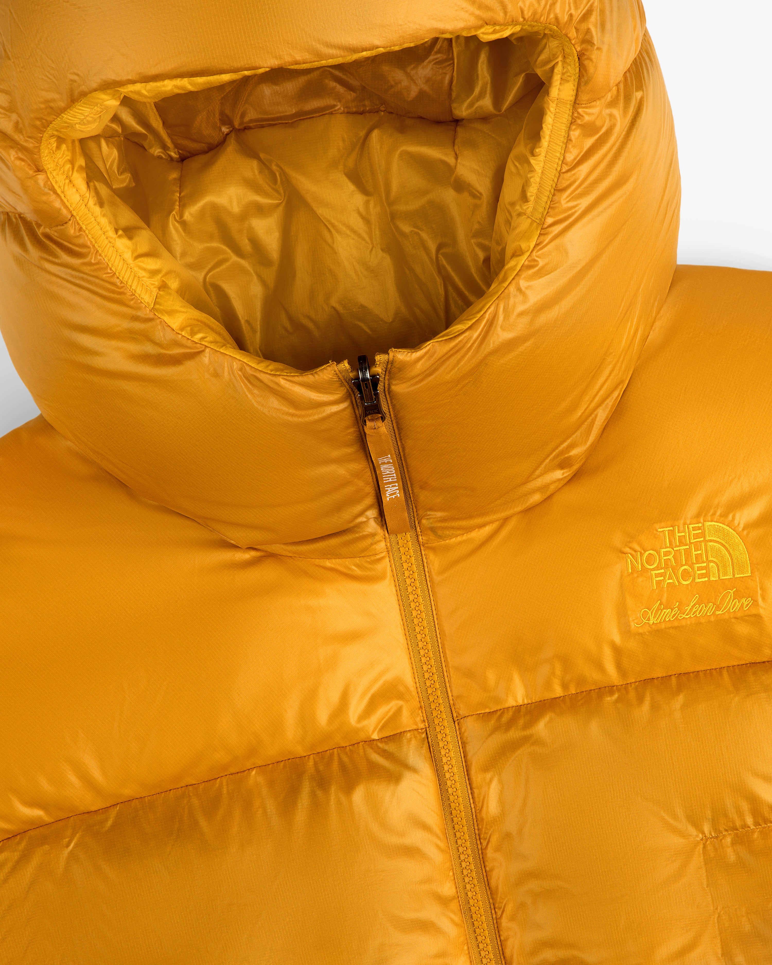 Close-up of a shiny yellow ALD/The North Face Reversible Pertex® Nuptse Jacket with hood and visible zipper.