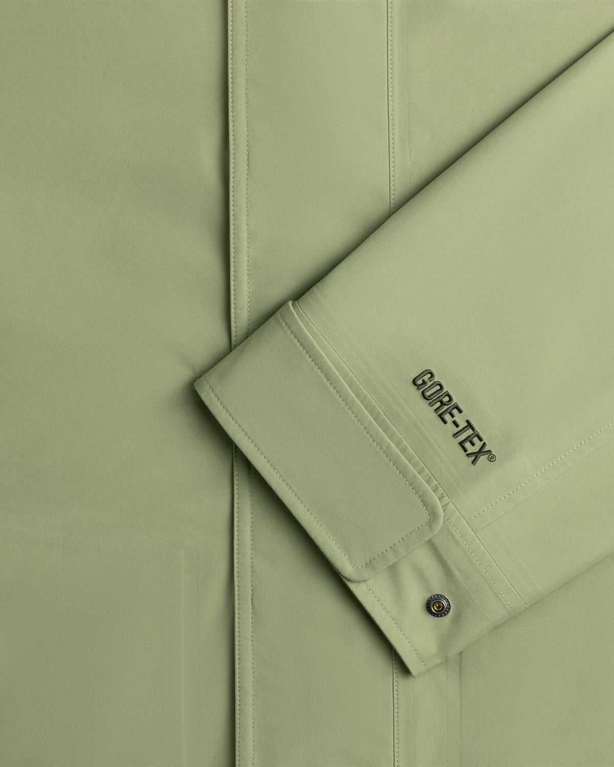 Close-up of ALD / The North Face GORE-TEX Trench Coat sleeve with branding and a metal snap button on the cuff.