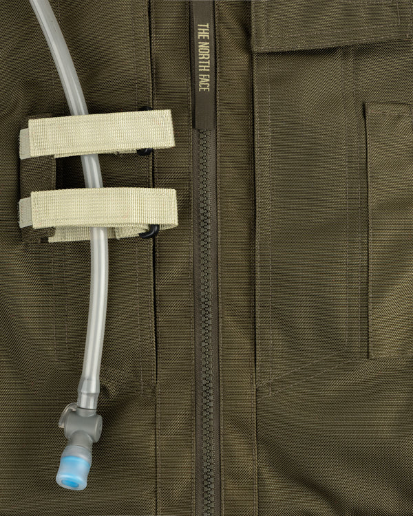Close-up of an olive green ALD / The North Face Ballistic Tech Vest with a hydration tube in beige straps.