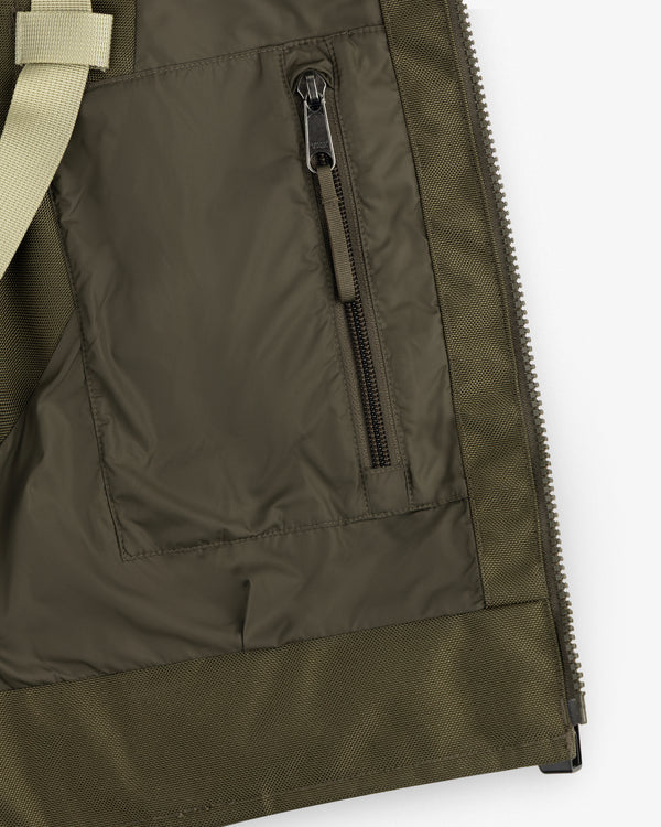 Close-up of the ALD / The North Face Ballistic Tech Vest pocket with vertical zipper and beige strap on the left.