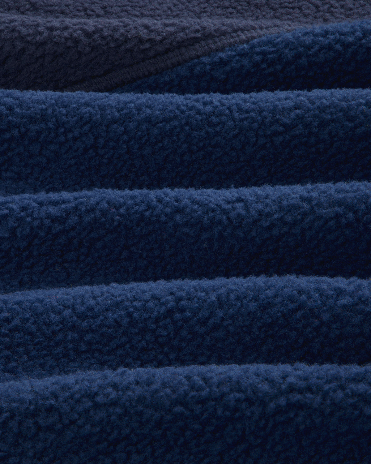 Close-up of ALD/The North Face ’95 Denali Half-Zip Fleece Pullover in deep blue, showing soft, wave-like folds.