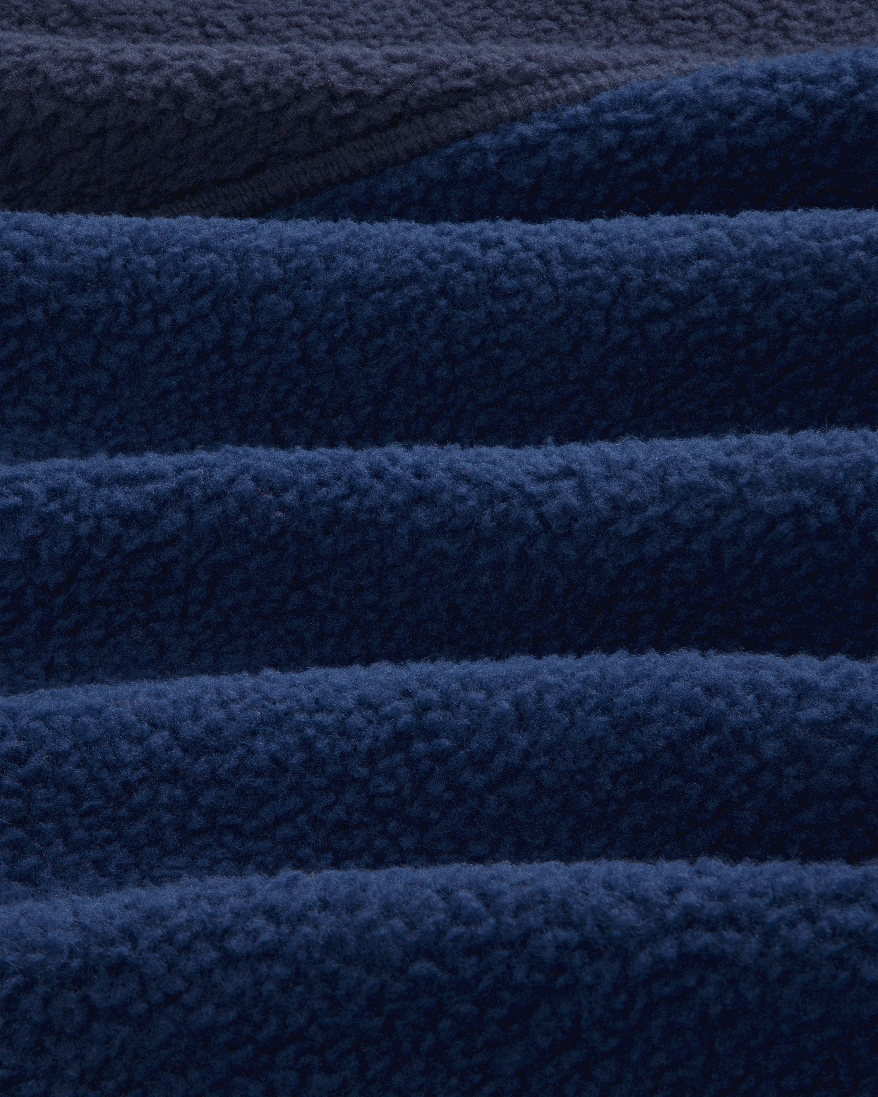 Close-up of ALD/The North Face ’95 Denali Half-Zip Fleece Pullover in deep blue, showing soft, wave-like folds.