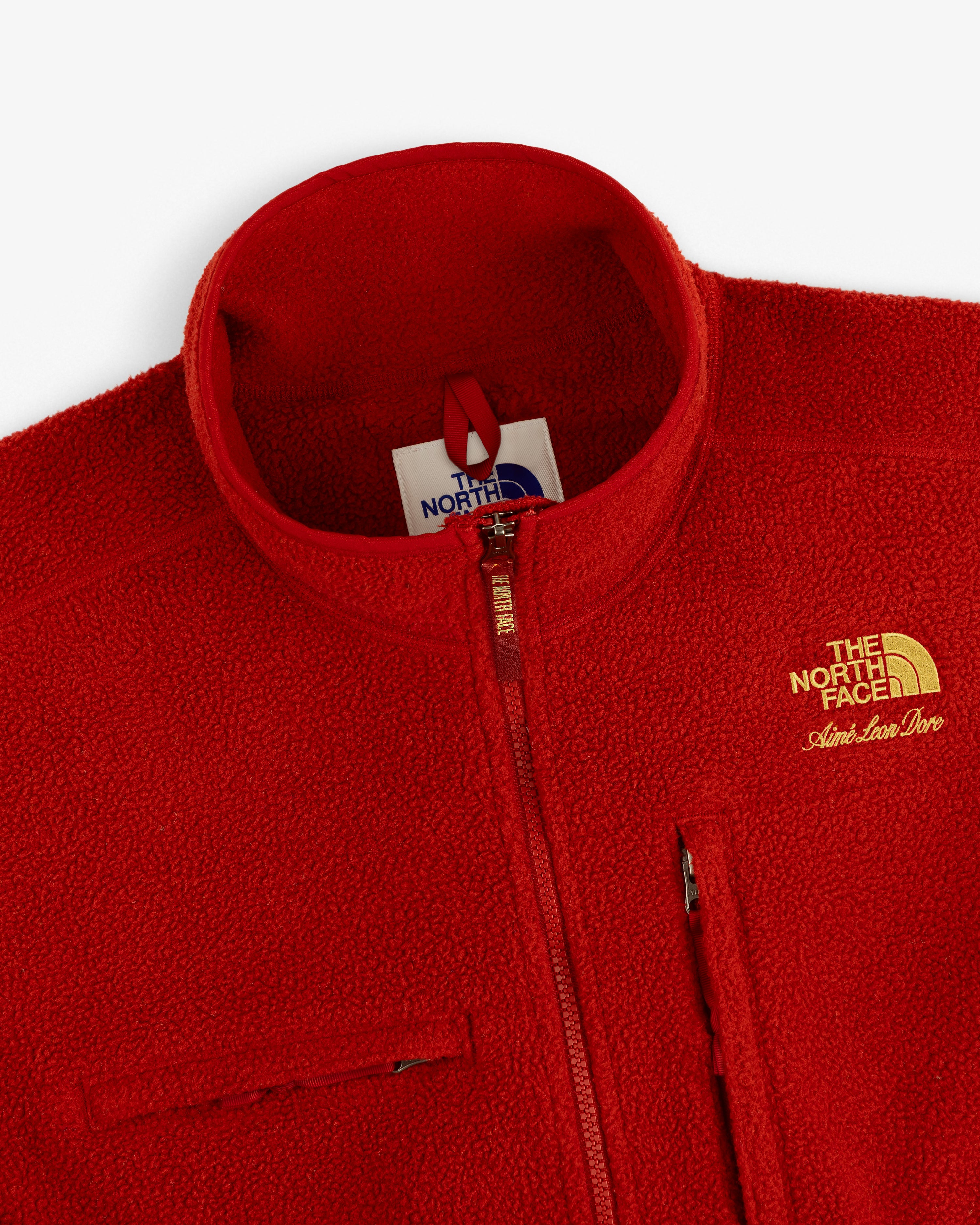 Red ALD/The North Face ’95 Denali Half-Zip Fleece Pullover with gold logo and chest zippers, top-front view.