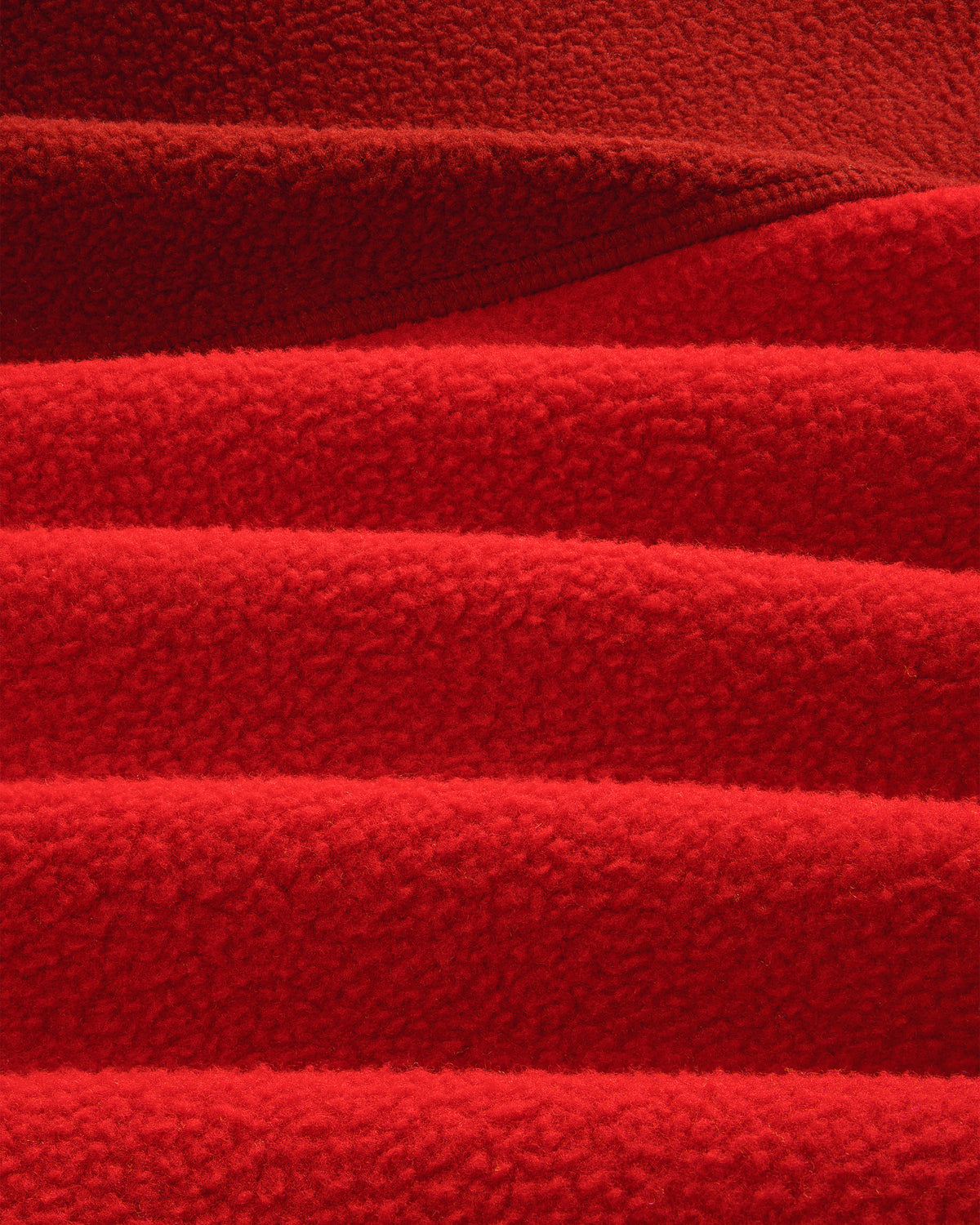 Detail of ALD / The North Face ’95 Denali Half-Zip Fleece Pullover: overlapping, textured red fleece with soft lines.