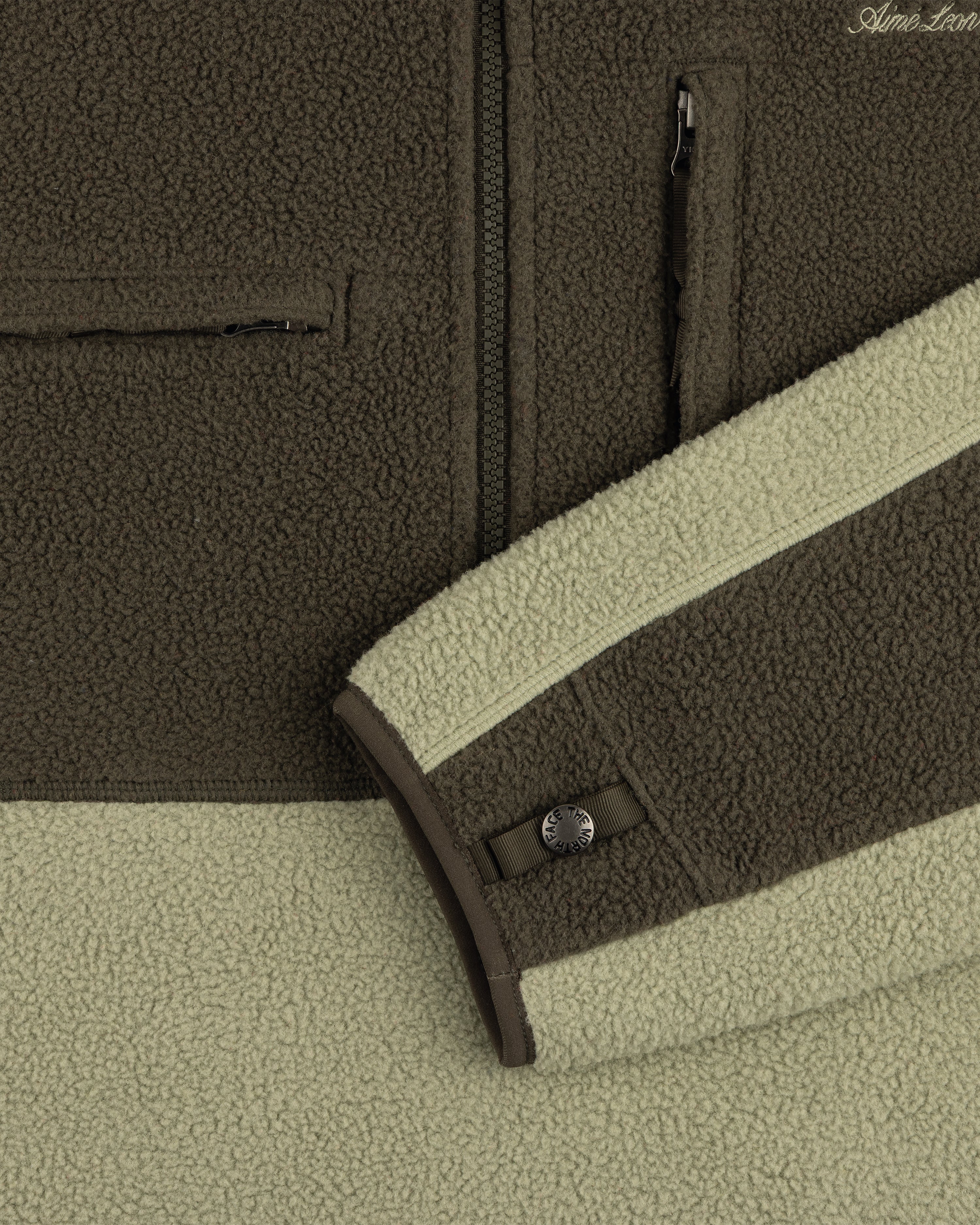 Close-up of ALD / The North Face ’95 Denali Half-Zip Fleece Pullover in olive/light green with zips and snap sleeve detail.