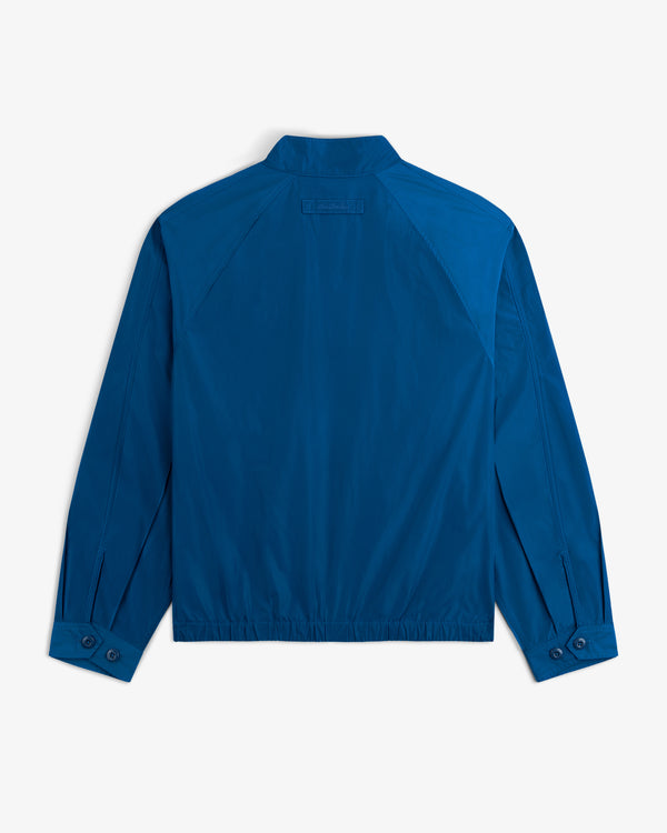 The Crest Nylon Windbreaker in blue, shown from the back, features a collar, buttoned cuffs, and stitched seams.
