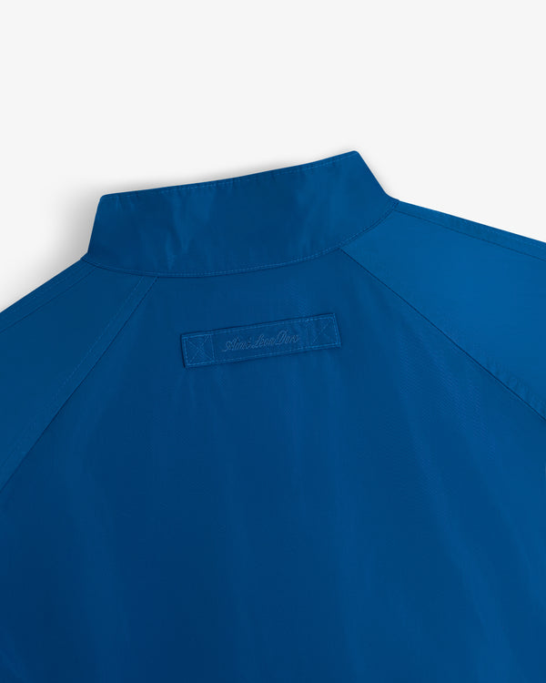 Close-up of the upper back of the Crest Nylon Windbreaker, blue with a stand collar and stitched rectangular patch.