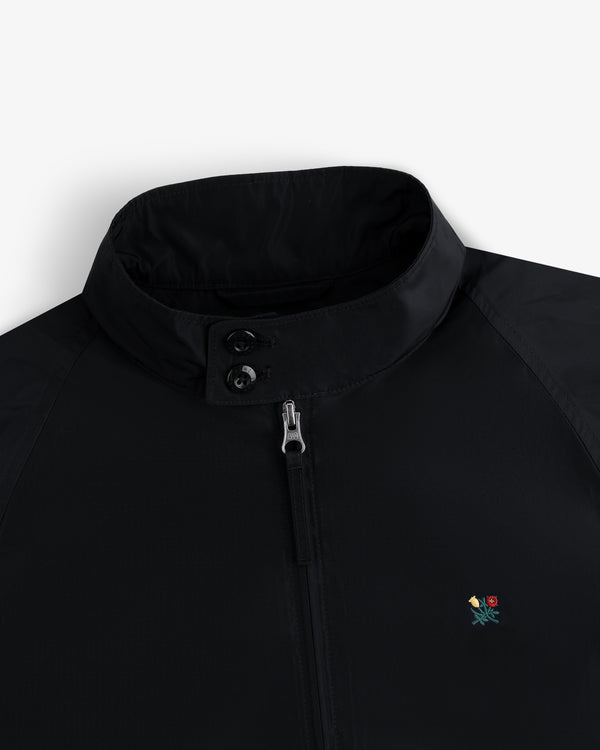 Crest Nylon Windbreaker: black, zip-up, two-collar buttons, small colorful flower embroidered on chest.