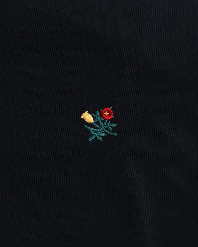 Small embroidered yellow and red flowers with green leaves on a black Crest Nylon Windbreaker.