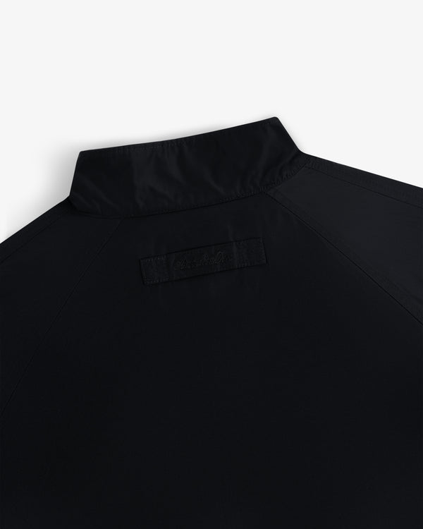 Back view of Crest Nylon Windbreaker in black, short collar, with subtle stitched branding below the collar.