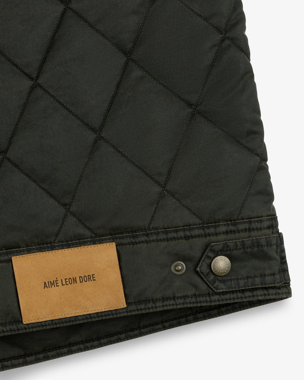 Dark green Quilted Trucker Jacket with a tan leather brand patch and a metal button on the hem.