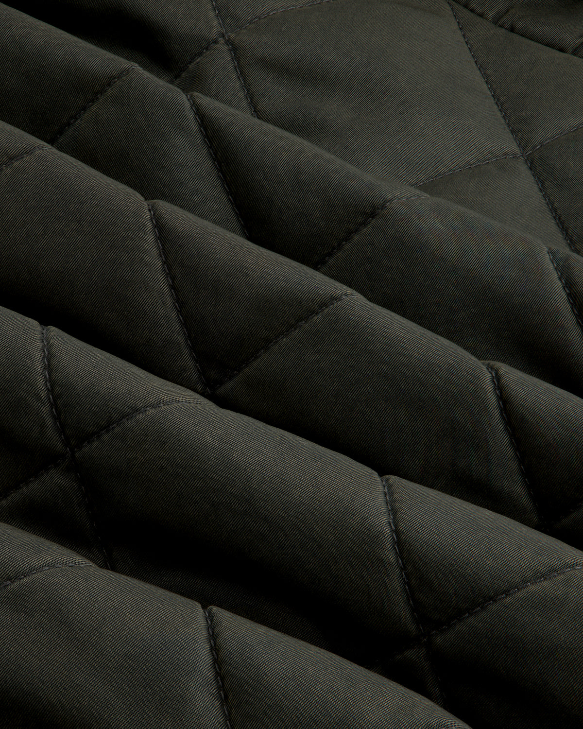 Close-up of olive green fabric on a Quilted Trucker Jacket with a diamond-patterned quilted texture.