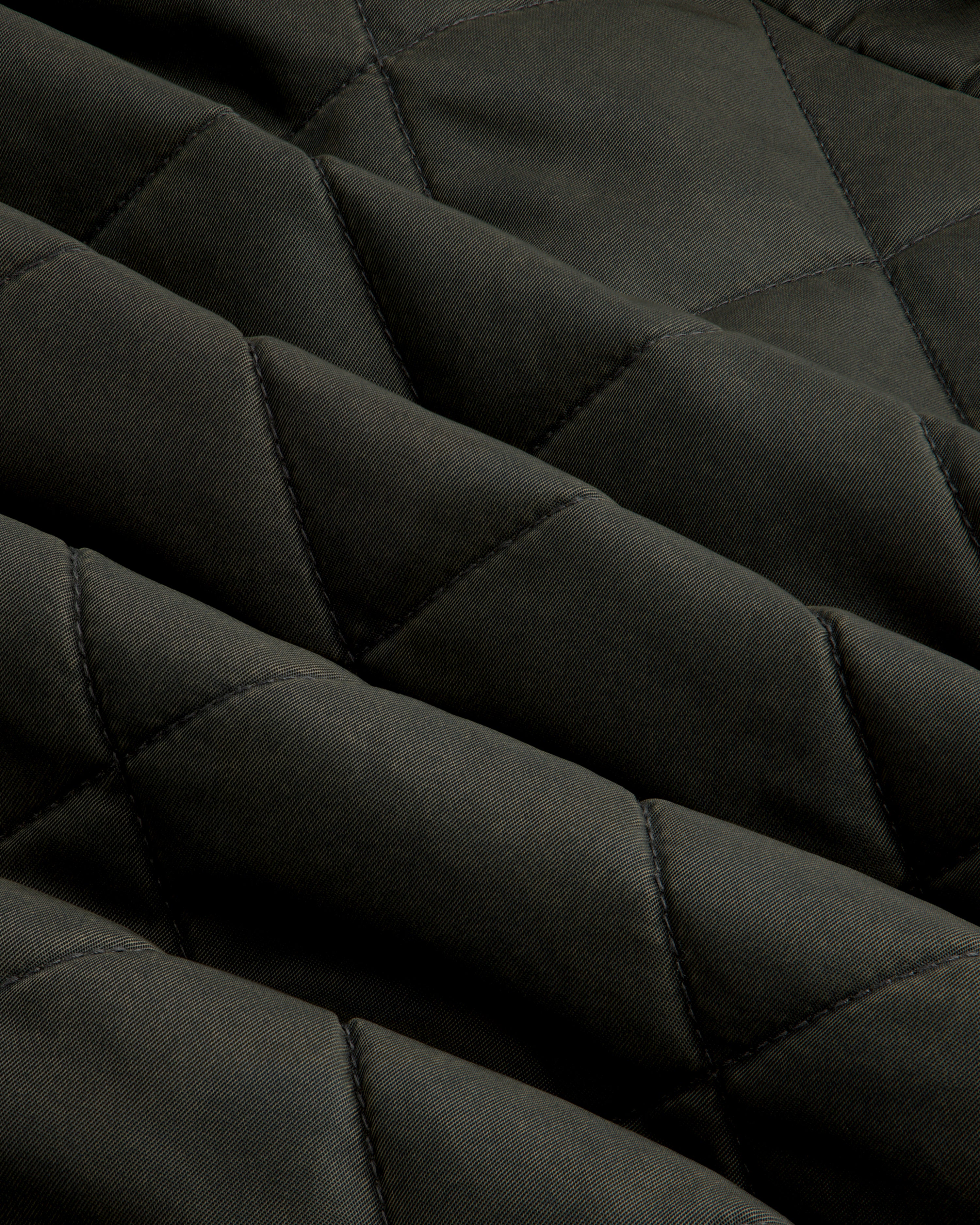 Close-up of olive green fabric on a Quilted Trucker Jacket with a diamond-patterned quilted texture.