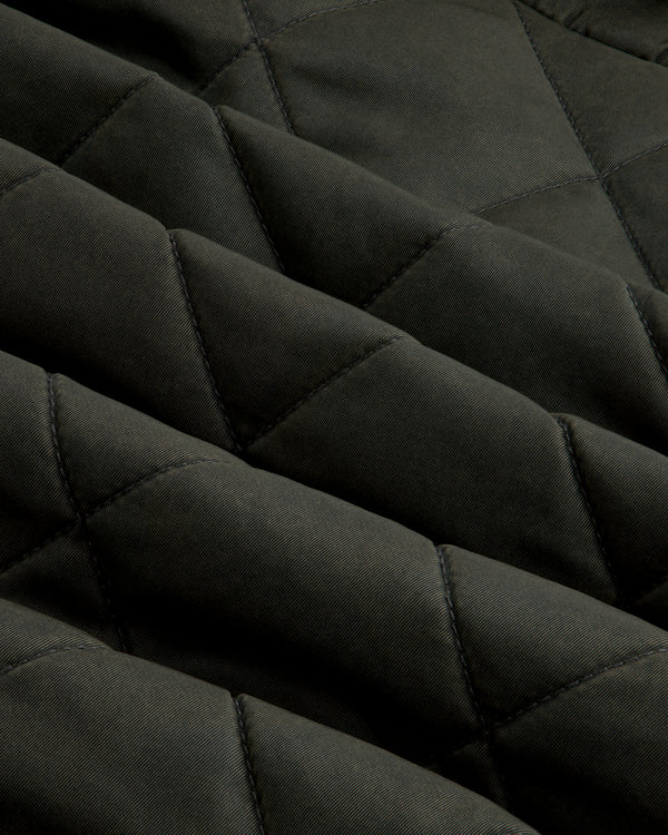 Close-up of olive green fabric on a Quilted Trucker Jacket with a diamond-patterned quilted texture.