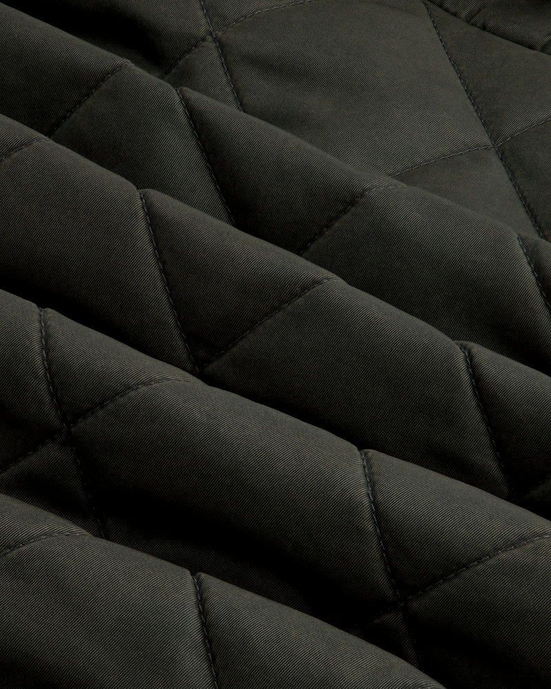 Close-up of olive green fabric on a Quilted Trucker Jacket with a diamond-patterned quilted texture.