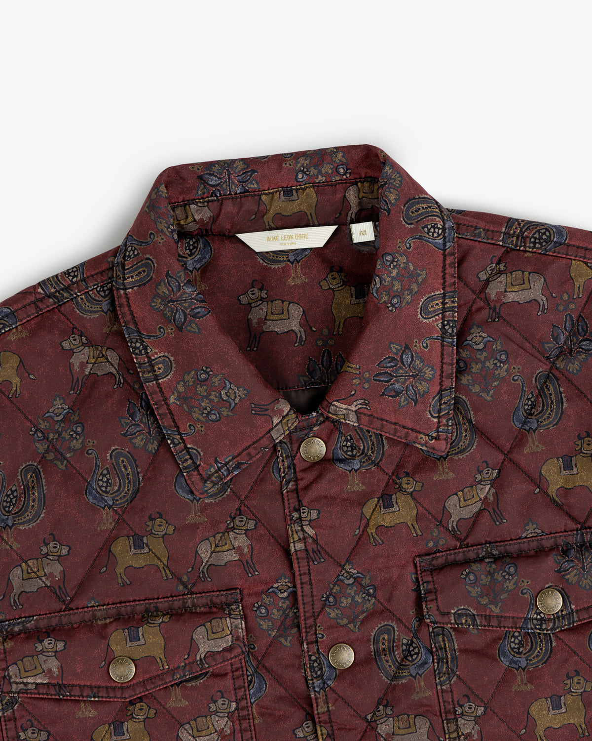 Maroon Quilted Trucker Jacket with a repeating cow and paisley pattern and metal button closures.