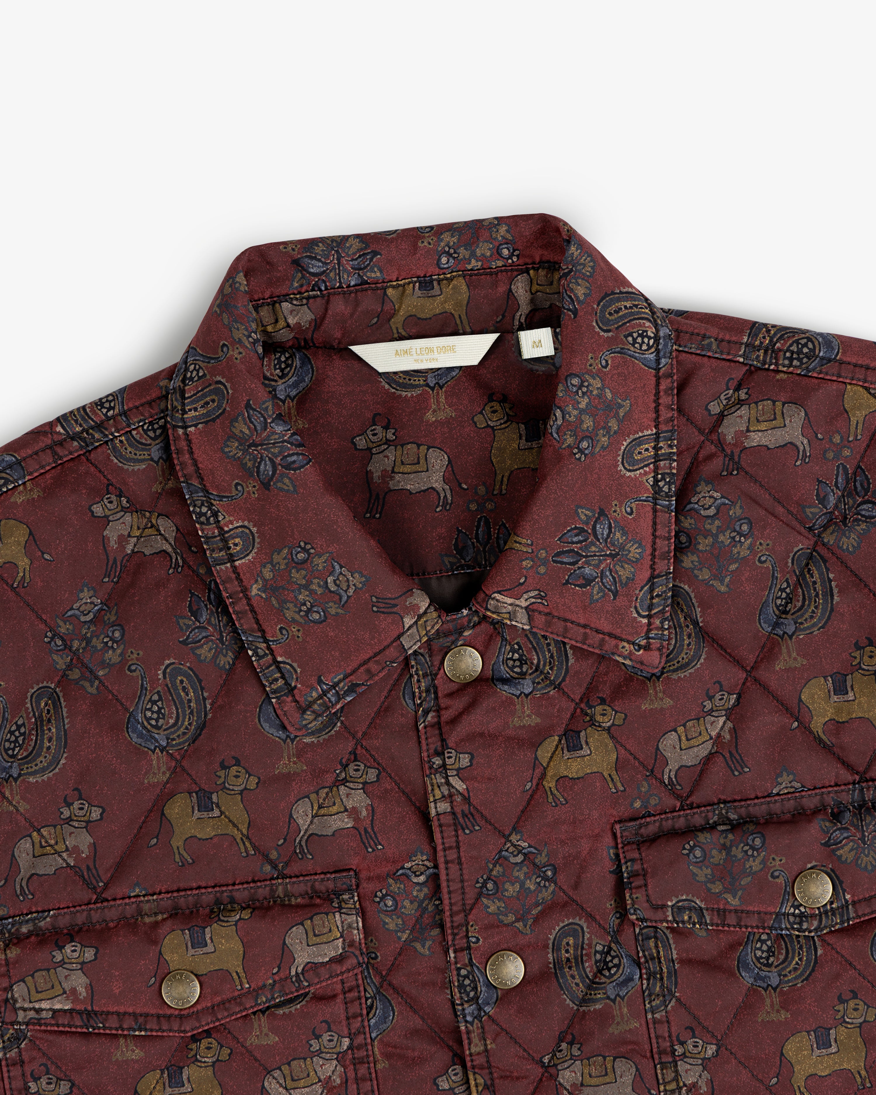 Maroon Quilted Trucker Jacket with a repeating cow and paisley pattern and metal button closures.