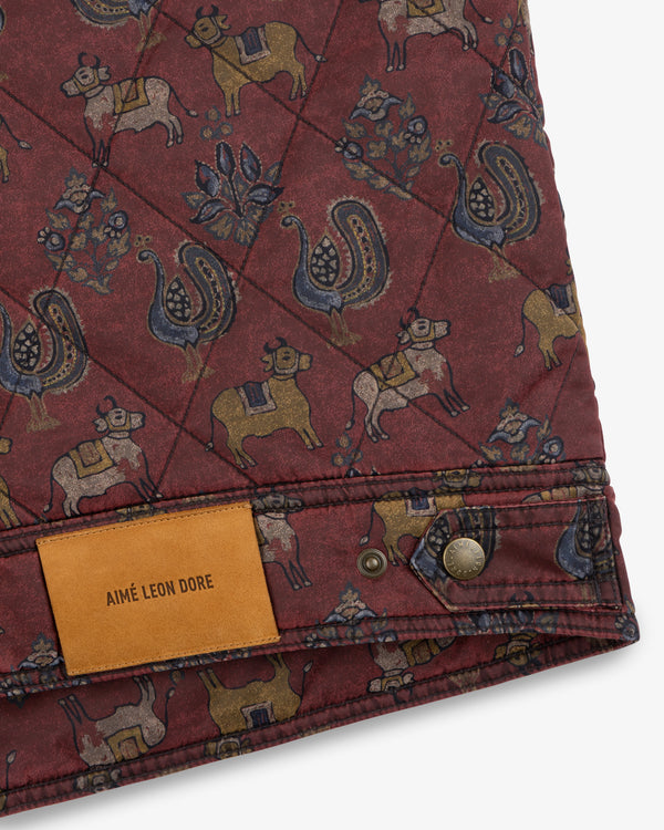 Quilted Trucker Jacket in maroon with a cow and peacock pattern, featuring a tan leather label and metal button.