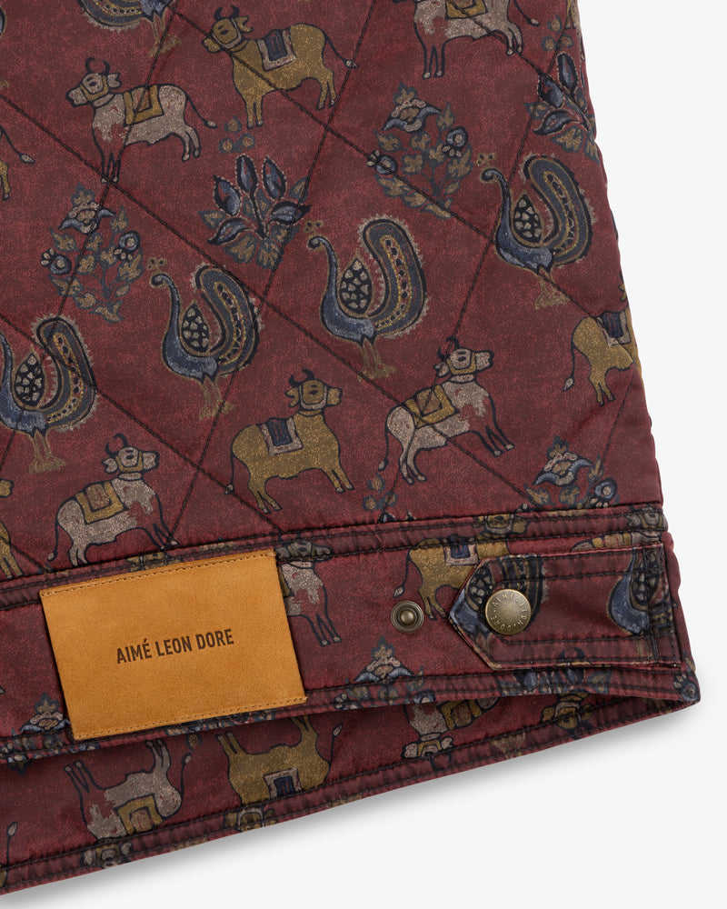 Quilted Trucker Jacket in maroon with a cow and peacock pattern, featuring a tan leather label and metal button.