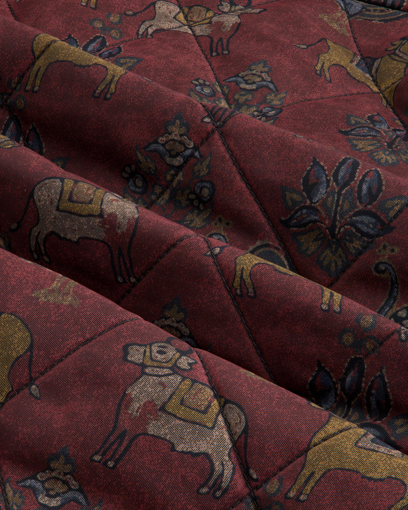 Quilted Trucker Jacket in deep red quilted fabric featuring a pattern of stylized animals and botanical motifs.