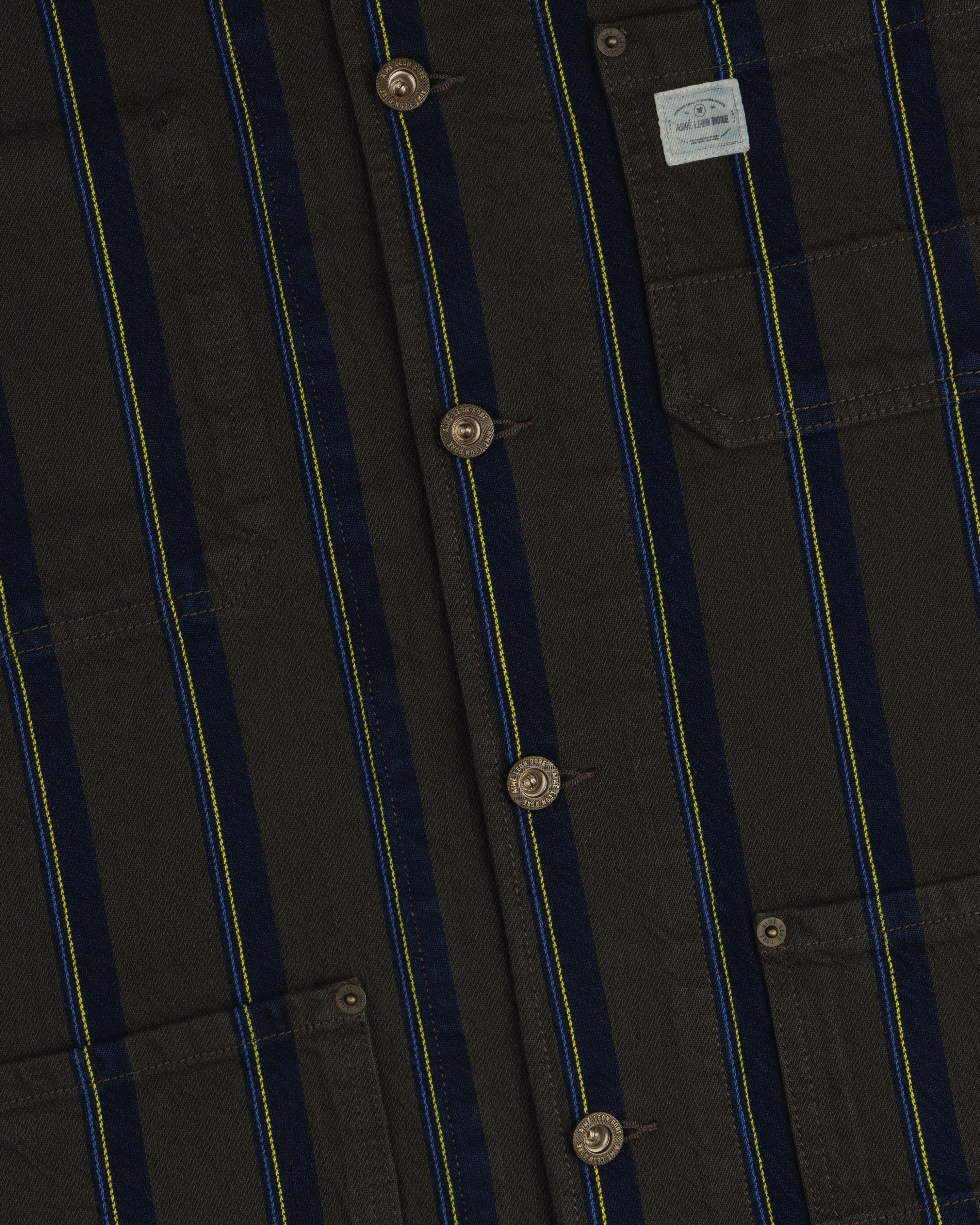 Close-up of the Striped Denim Chore Jacket with blue/yellow stripes, brown buttons, and a pocket label.