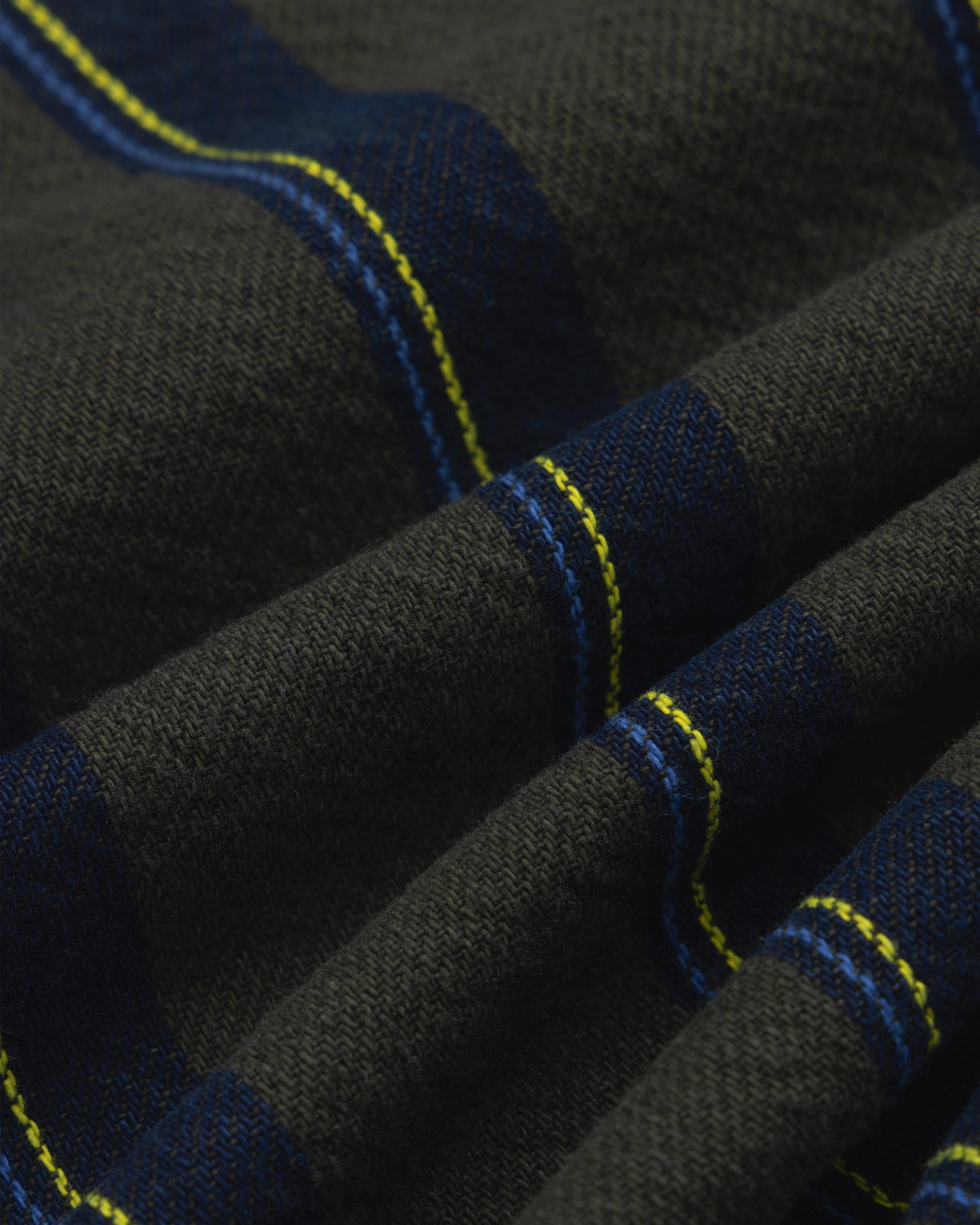 Close-up of Striped Denim Chore Jacket with blue and yellow plaid, showing fabric texture and diagonal folds.