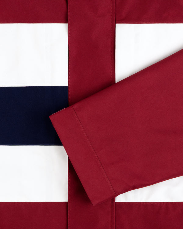A GORE-TEX Striped Sailing Jacket lies on white, navy, and maroon horizontal stripes.