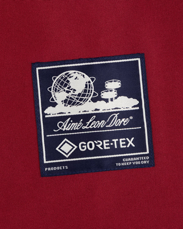 Navy GORE-TEX Striped Sailing Jacket patch on red with globe, cloud graphics, and white Aimé Leon Dore text.