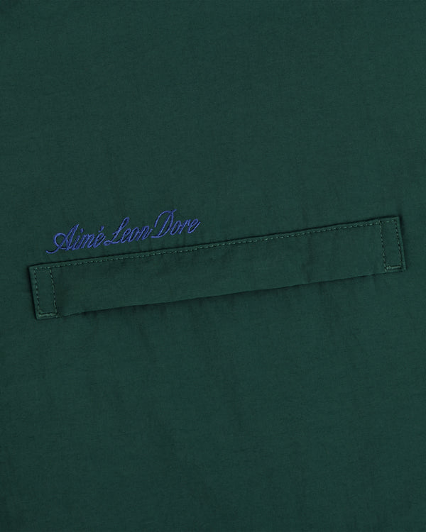 Green fleece lined sport windbreaker with blue Aimé Leon Dore cursive above a stitched horizontal fabric tab.
