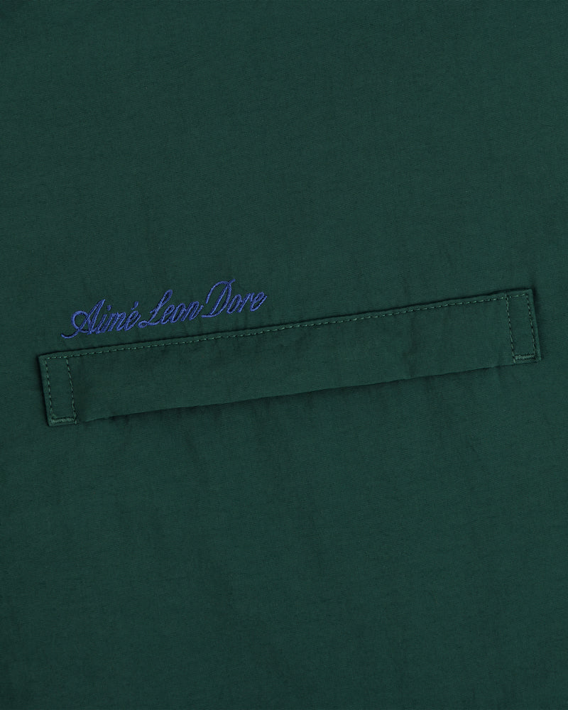 Green fleece lined sport windbreaker with blue Aimé Leon Dore cursive above a stitched horizontal fabric tab.