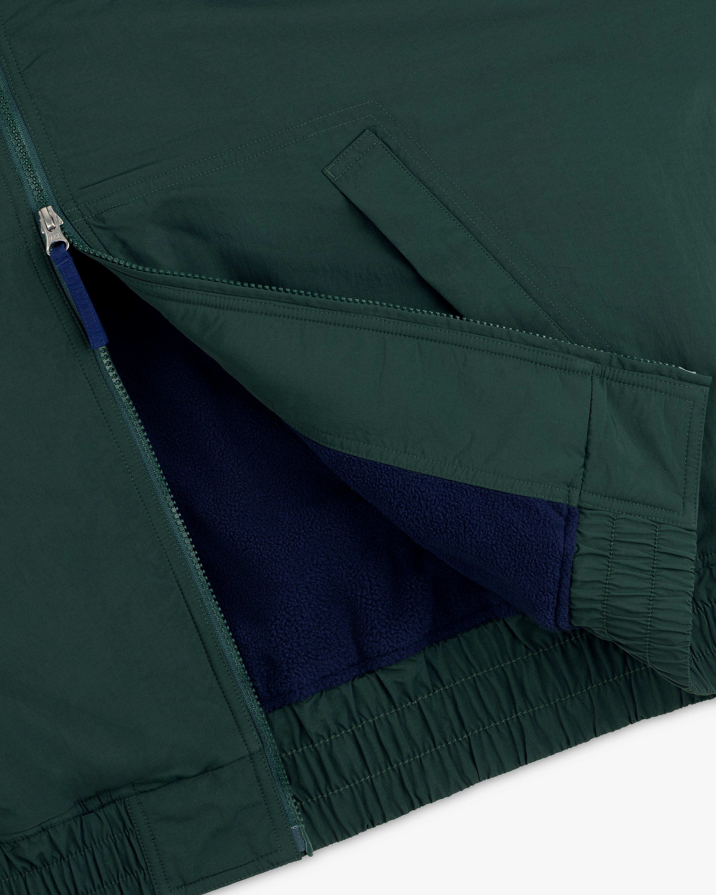 Close-up of Fleece Lined Sport Windbreaker: green shell, blue fleece lining, open zipper, and angled front pocket.