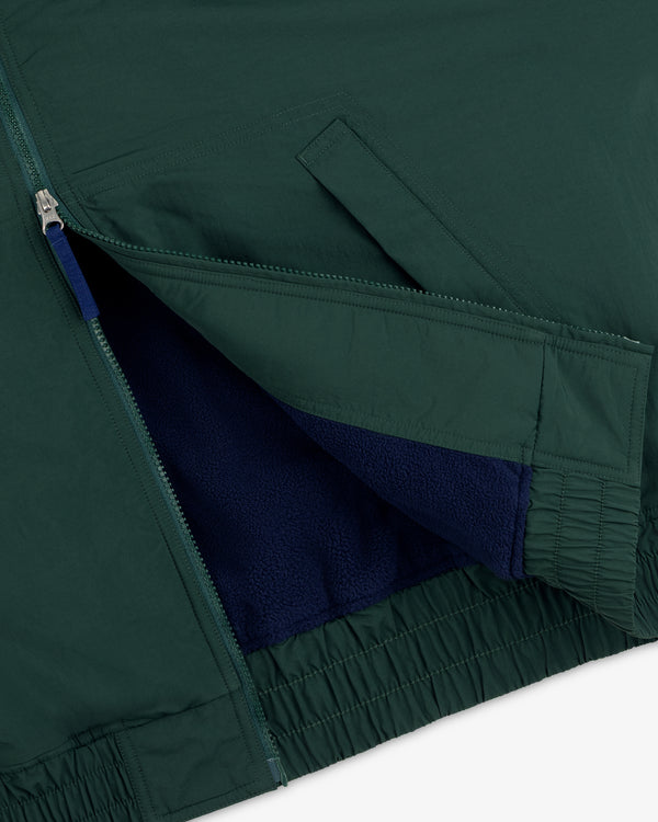 Close-up of Fleece Lined Sport Windbreaker: green shell, blue fleece lining, open zipper, and angled front pocket.