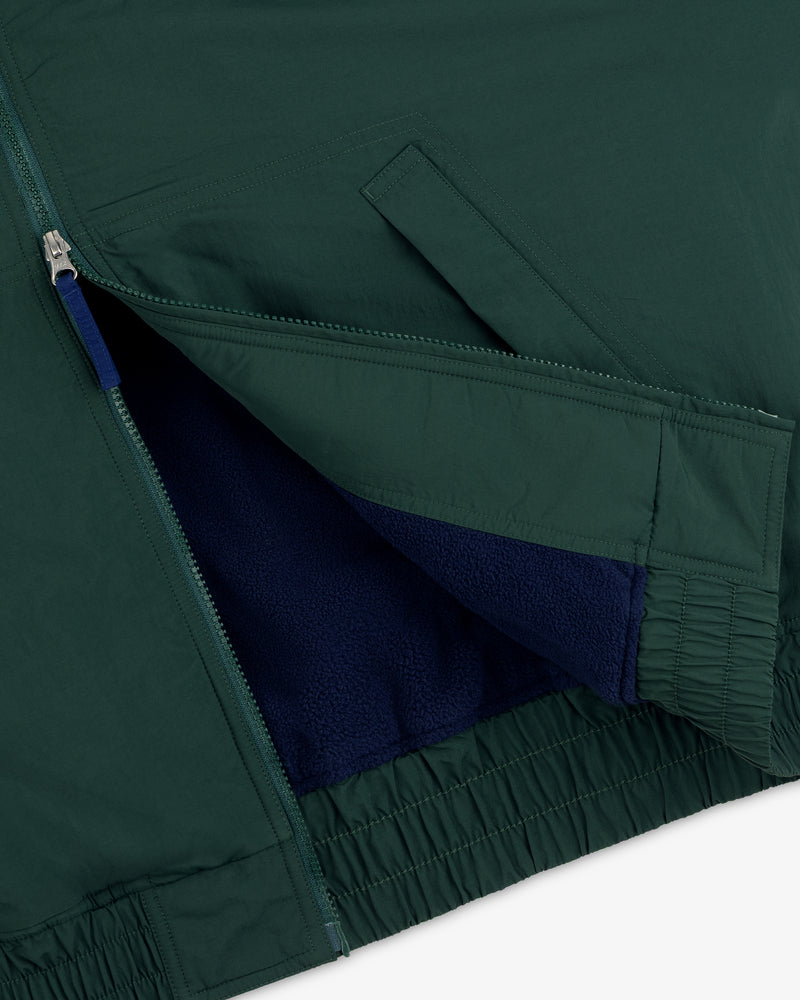 Close-up of Fleece Lined Sport Windbreaker: green shell, blue fleece lining, open zipper, and angled front pocket.