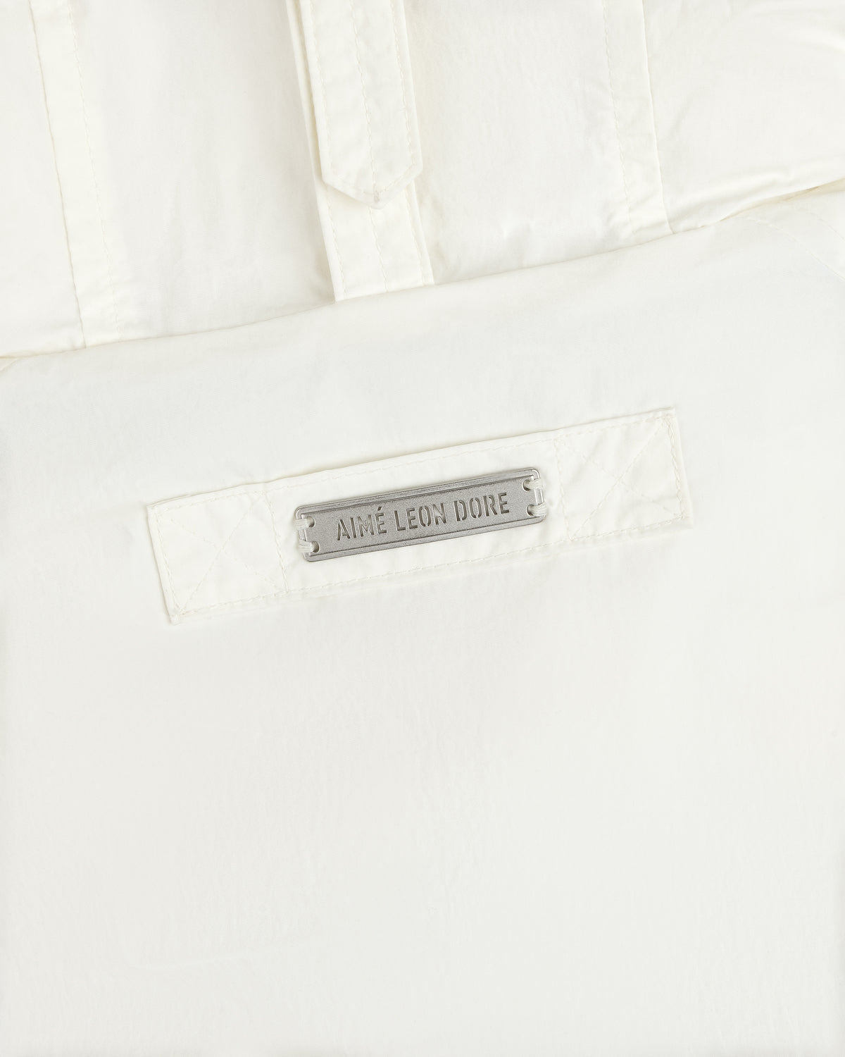 White Down-Filled Surplus Parka with a metallic brand name tag on the front pocket.