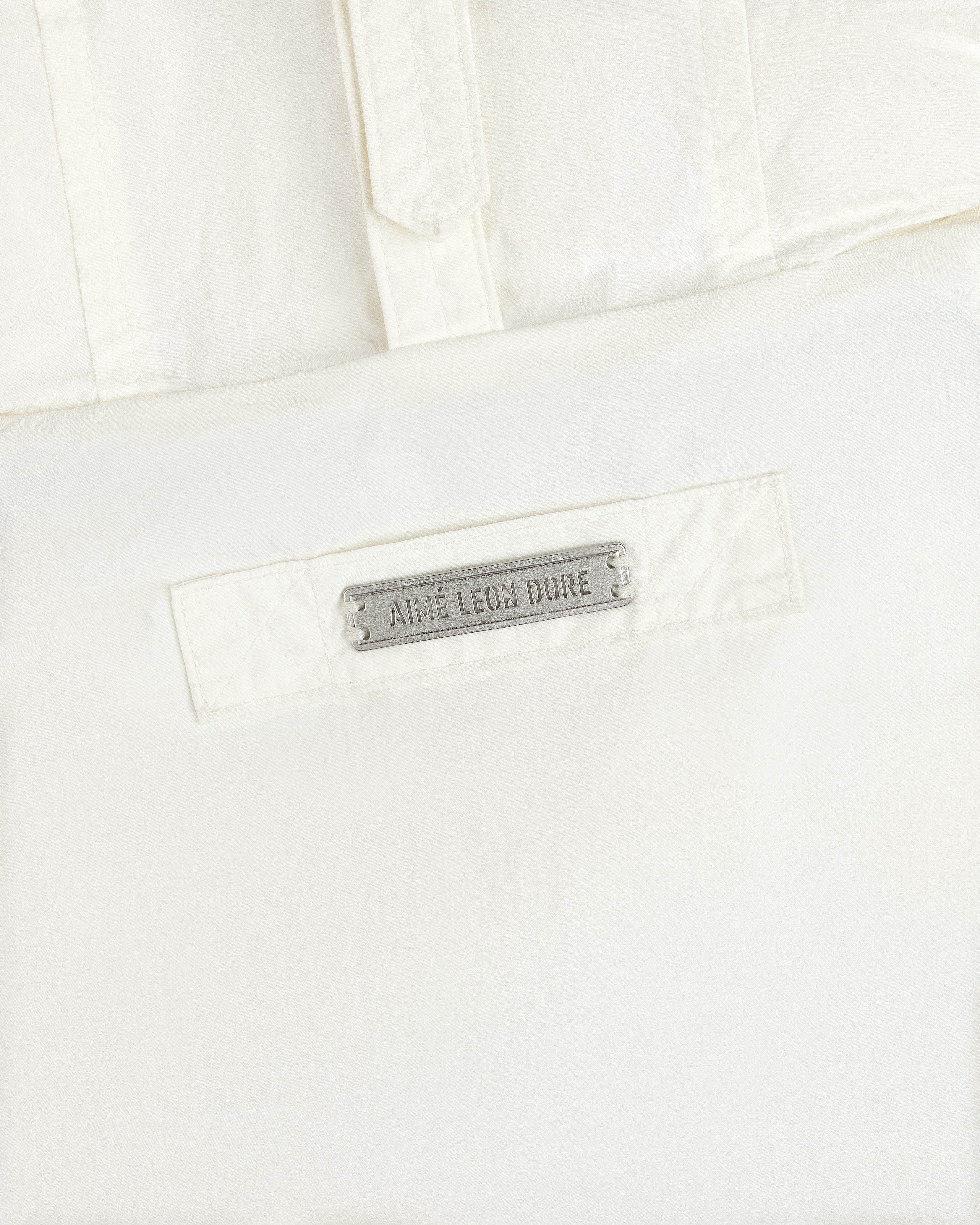 White Down-Filled Surplus Parka with a metallic brand name tag on the front pocket.