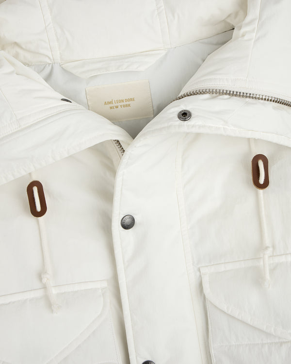 Close-up of a white Down-Filled Surplus Parka with a zipper, button placket, two front pockets, and brown drawstring toggles.