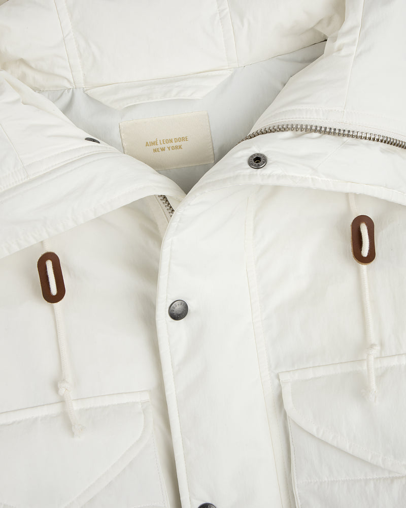 Close-up of a white Down-Filled Surplus Parka with a zipper, button placket, two front pockets, and brown drawstring toggles.